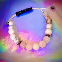 a pink and white beaded bracelet on a colorful background